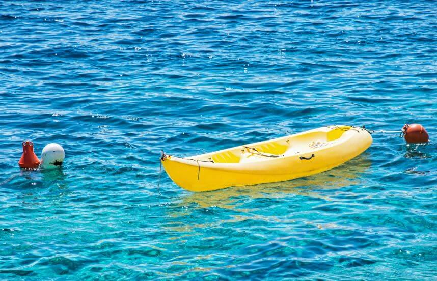 Yellow kayak in the ocean with three bouys around it, under are kayak anchors.