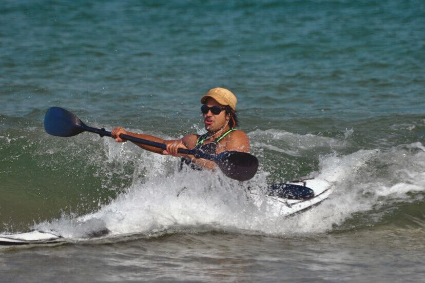 A man on a sit in kayak in the ocean, surf kayaking.